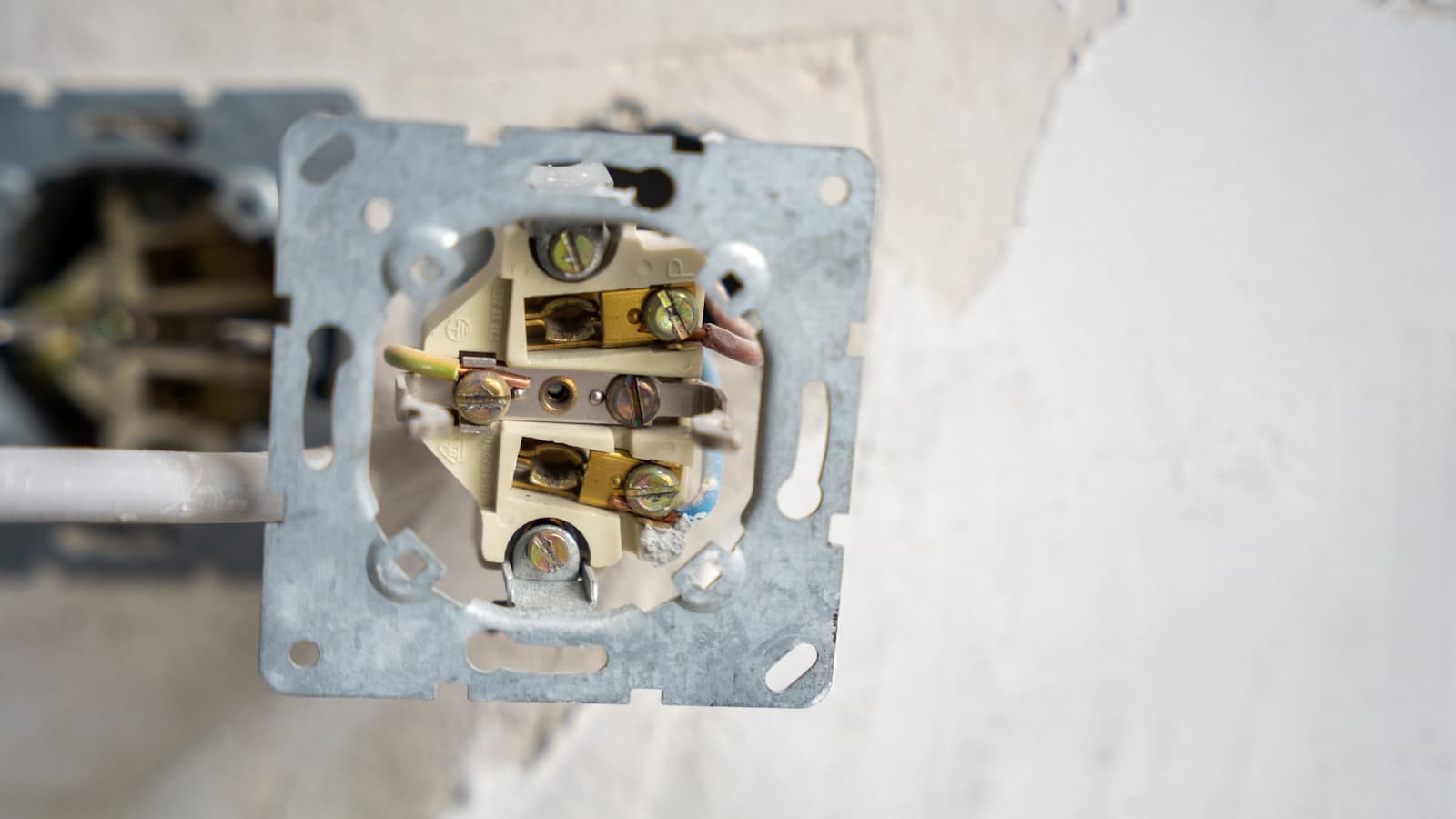 Electrical outlet pulled from the wall exposing wiring — a sign to call an electrician